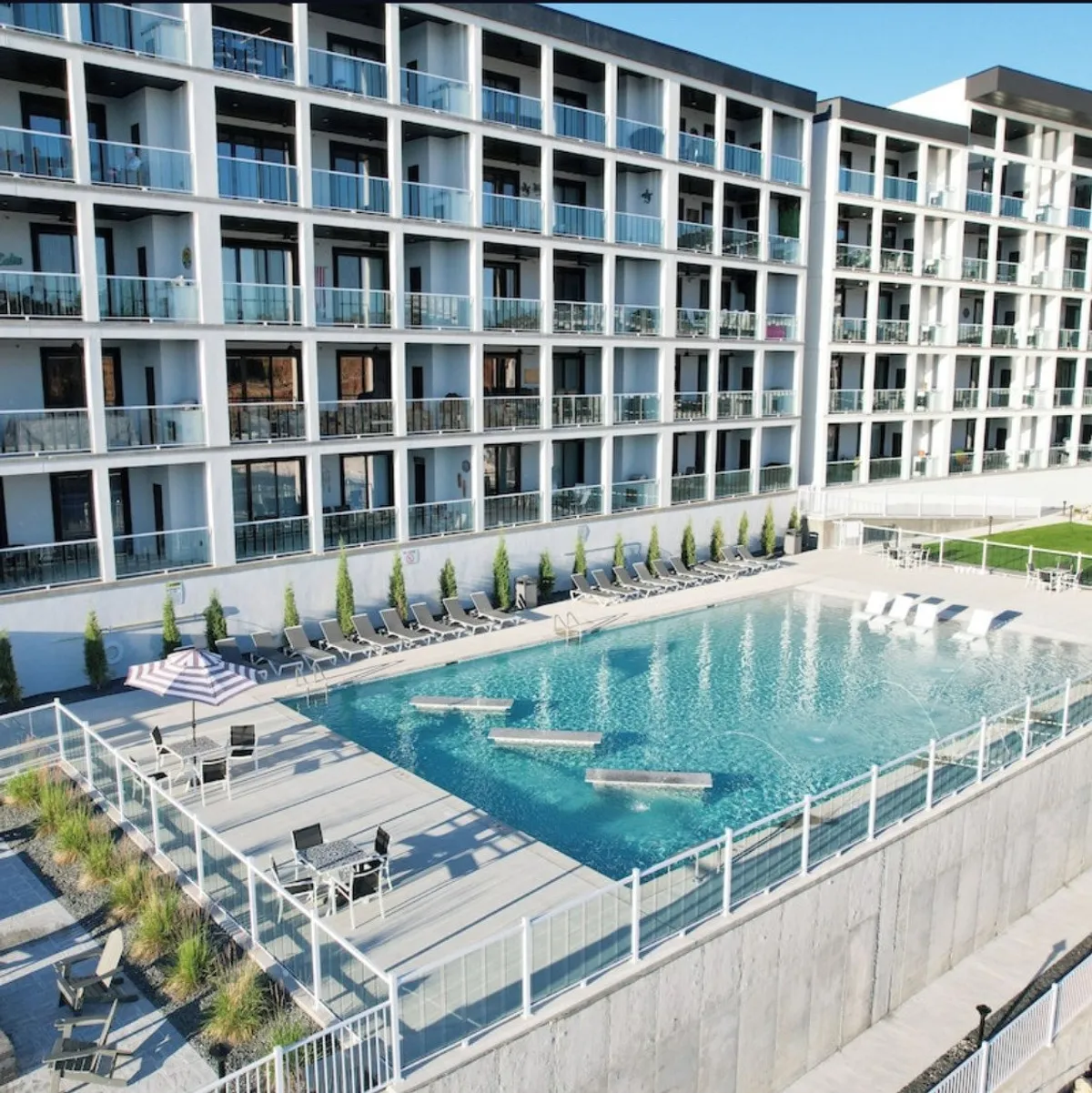 A tranquil scene of the resort's swimming pool surrounded by lounge chairs and the balconies of the condominium building in the background. The pool area is spacious, inviting, and designed for group relaxation and social gatherings.