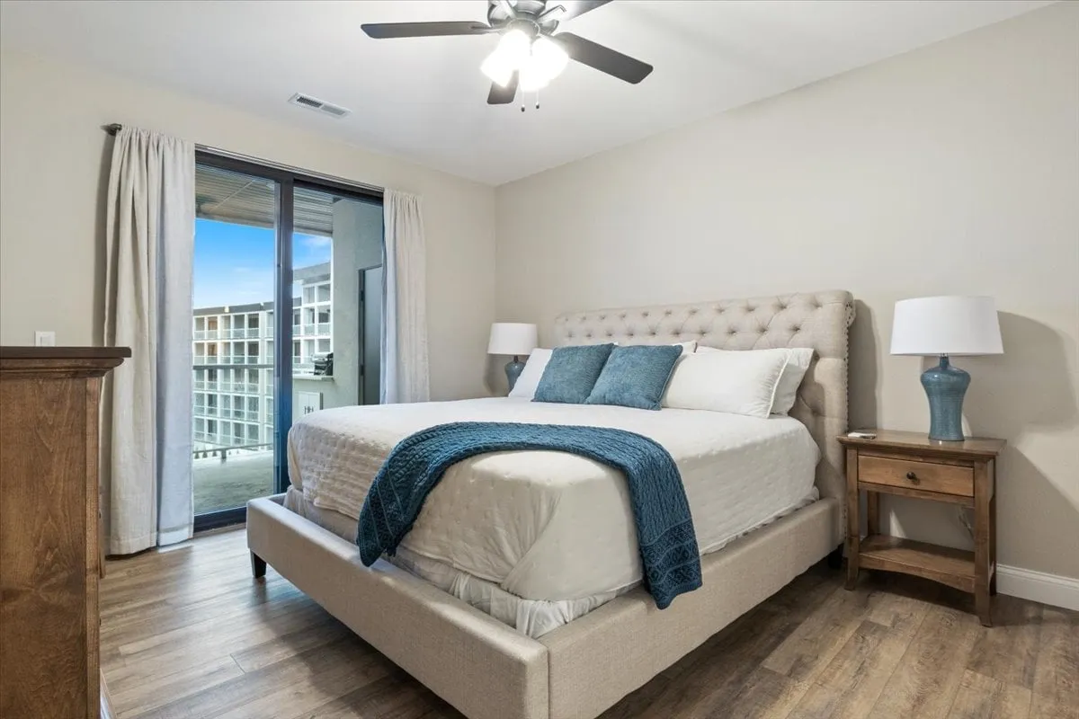 A serene master bedroom with a plush bed, nightstand with lamps, and access to a private balcony. The room is bathed in natural light, providing a peaceful retreat for parents to relax and enjoy beautiful morning views.