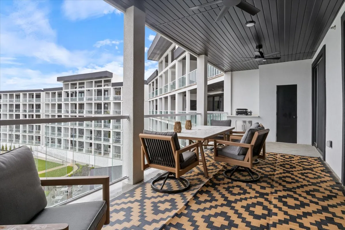 An outdoor dining table with stylish chairs set against patterned tile flooring, offering a welcoming space for al fresco meals and group gatherings. Decorative vases add a touch of elegance, while the open-air setting hints at lake views nearby.