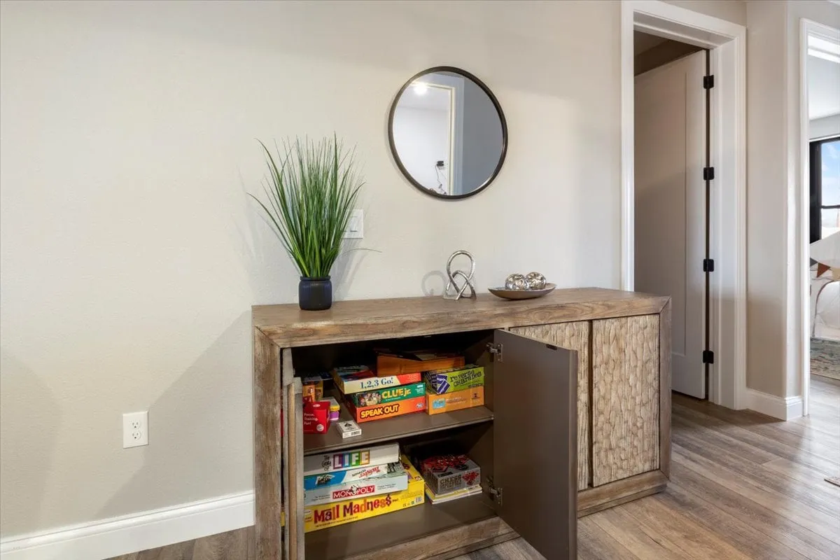 A cozy nook with a wooden cabinet, decorative plant, and a stack of board games ready for friendly family competition. The setting encourages togetherness, laughter, and memorable bonding moments for all ages.